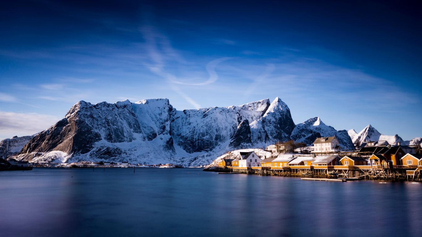 Красивый вид на дома у заснеженных гор под голубым небом 