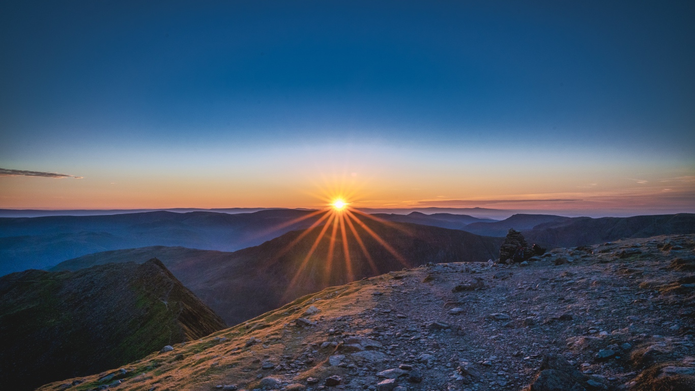 Рассвет яркого солнца в голубом небе над горами