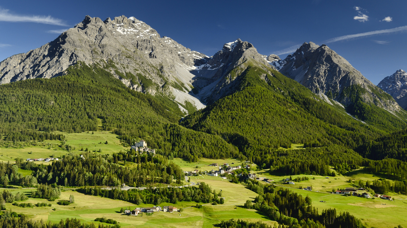 Высокие швейцарские Альпы покрыты зеленью под голубым небом 