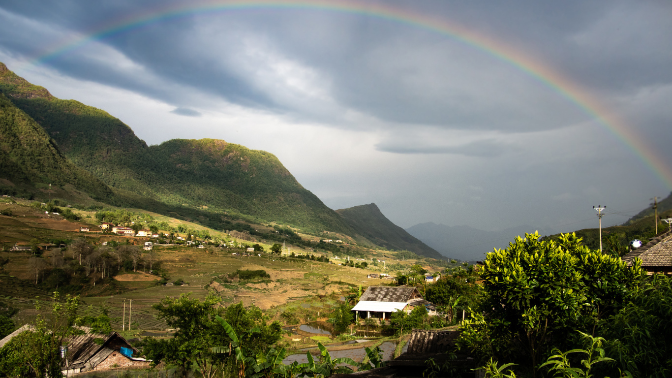 Большая разноцветная радуга в небе над горами