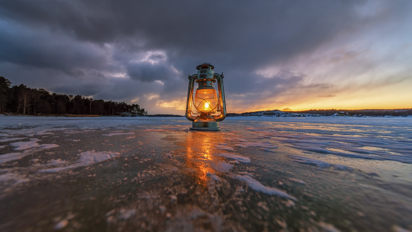 Керосиновая лампа стоит на покрытом льдом берегу