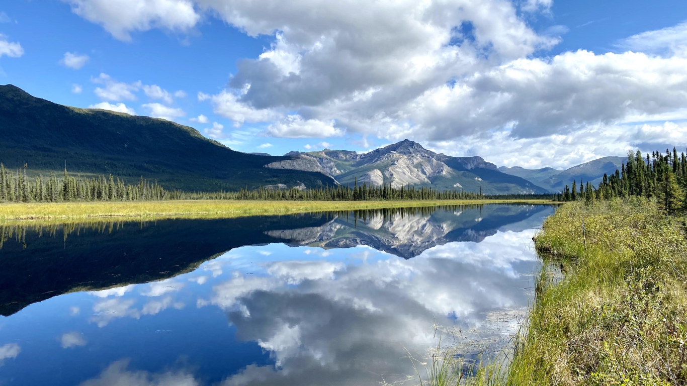 Небо с белыми облаками отражается в реке 
