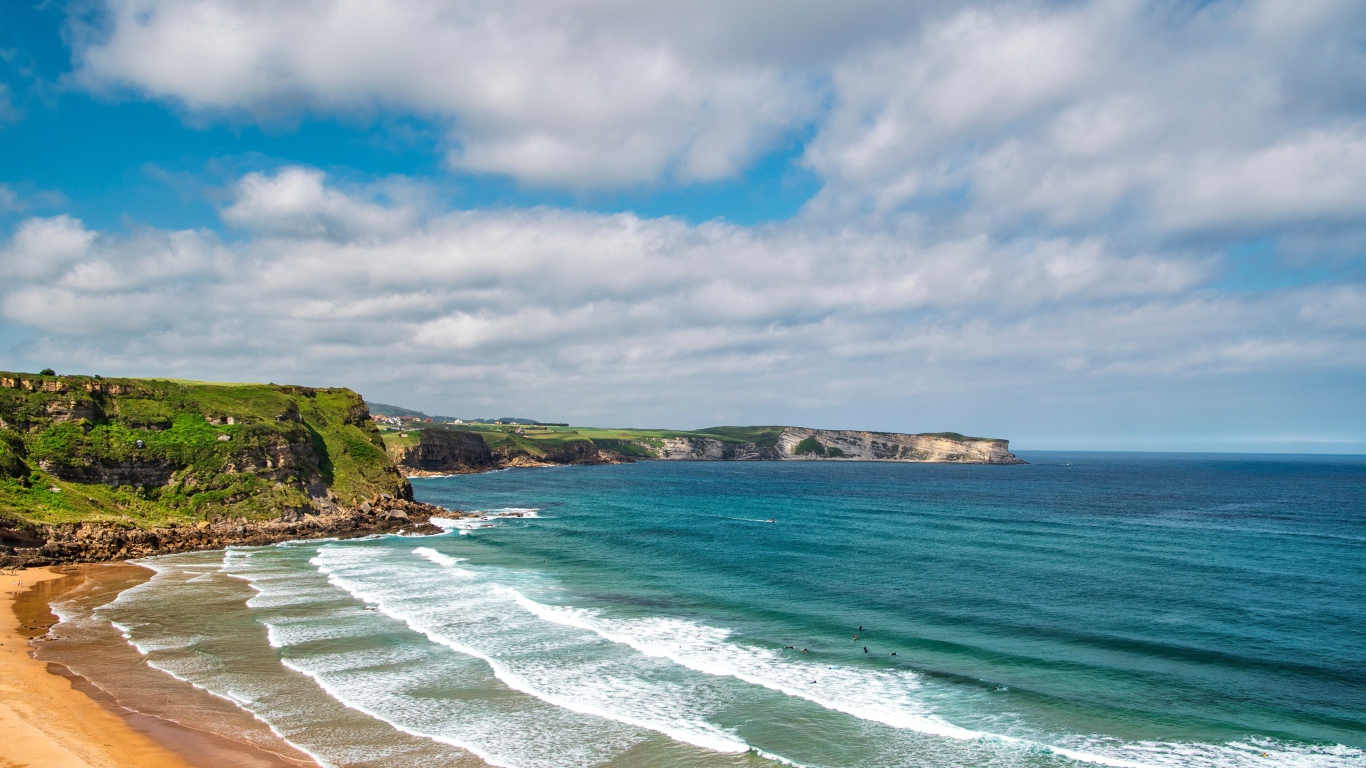Спокойные волны на берегу залива под голубым небом с облаками
