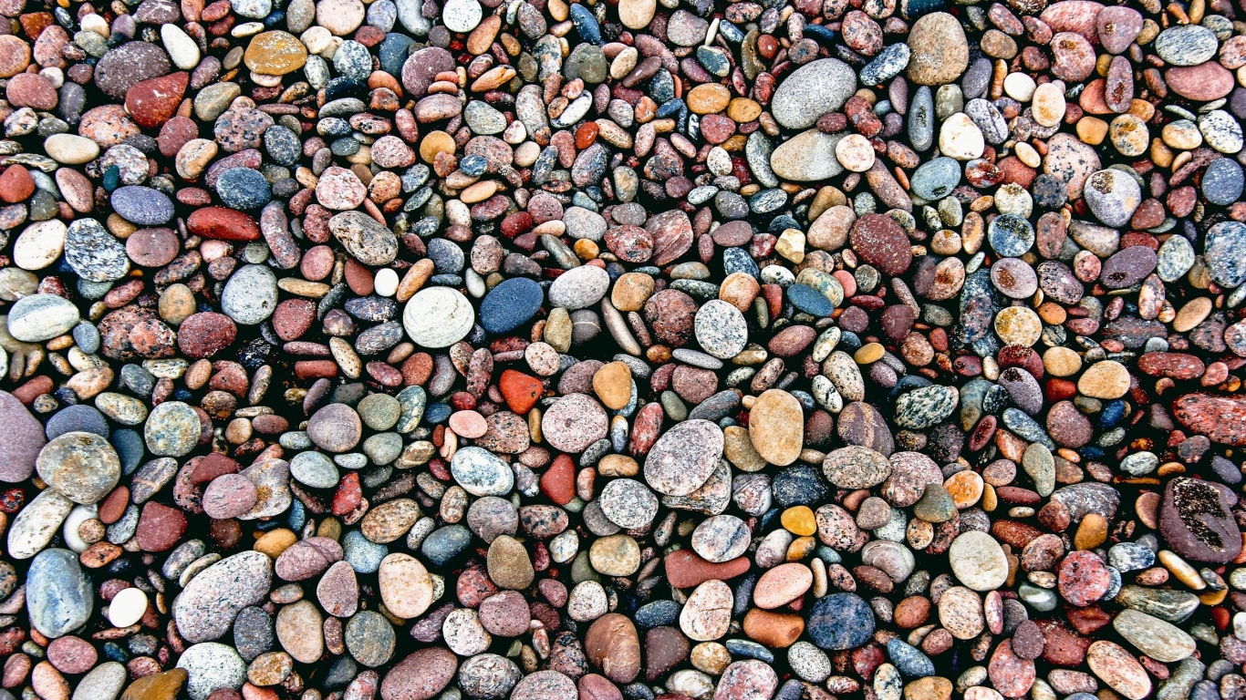 Мелкие разноцветные камни на морском берегу 