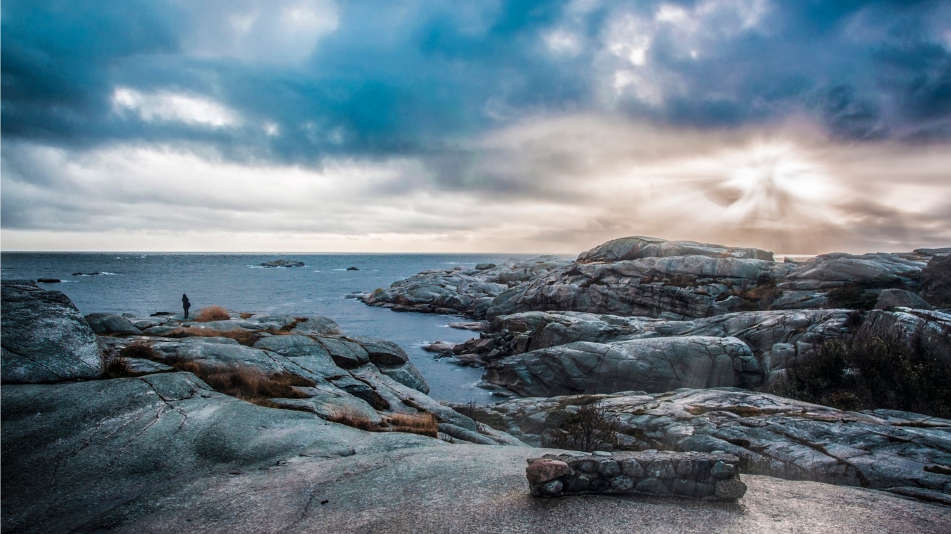 Каменный берег у тихого моря под черными облаками