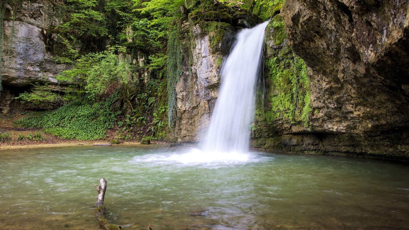 Водопад стекает с крутой горы в озеро 