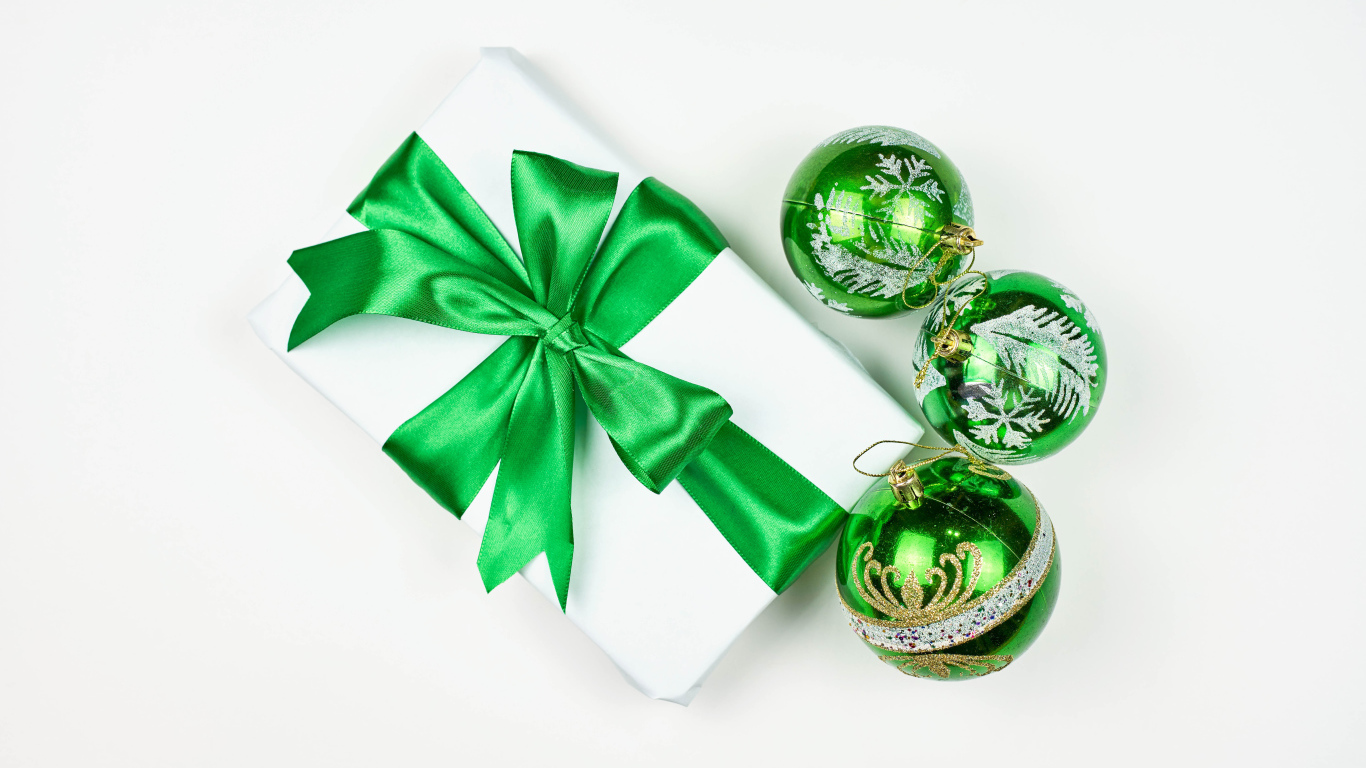 Подарок и три елочных шара на белом фоне 