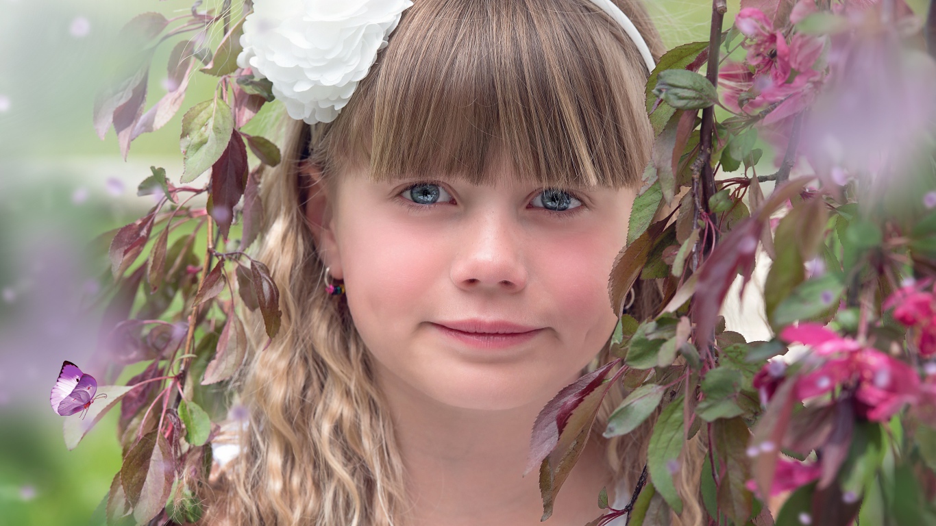 Красивая голубоглазая девочка с белым цветком на голове 