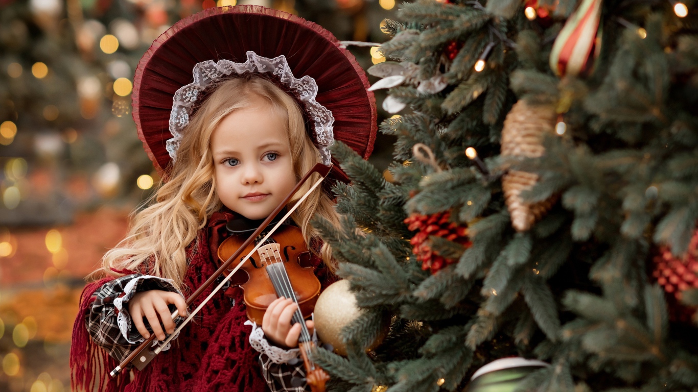 Красивая маленькая девочка со скрипкой у ели