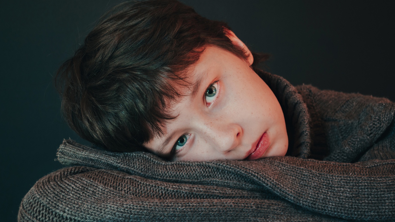 Мальчик в теплом свитере на сером фоне 