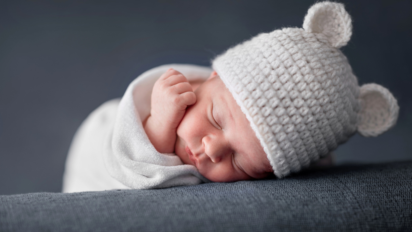 Милый спящий ребенок в белой шапке с ушками