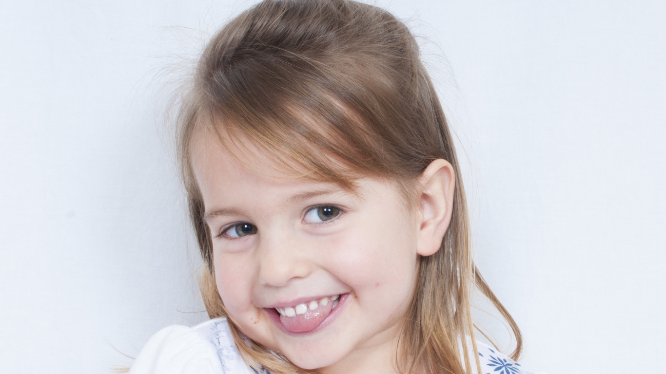 Милая улыбающаяся девочка с высунутым языком