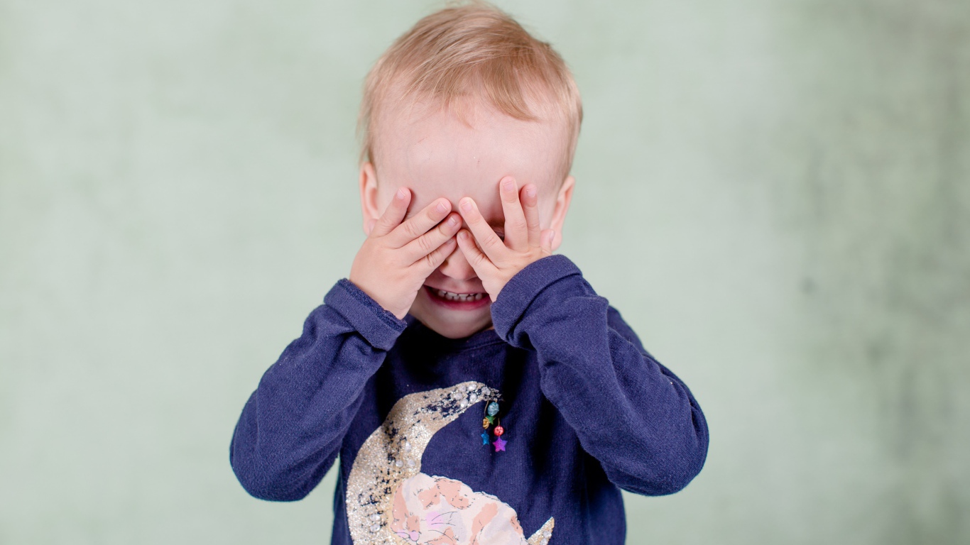 Маленький мальчик закрыл руками лицо 