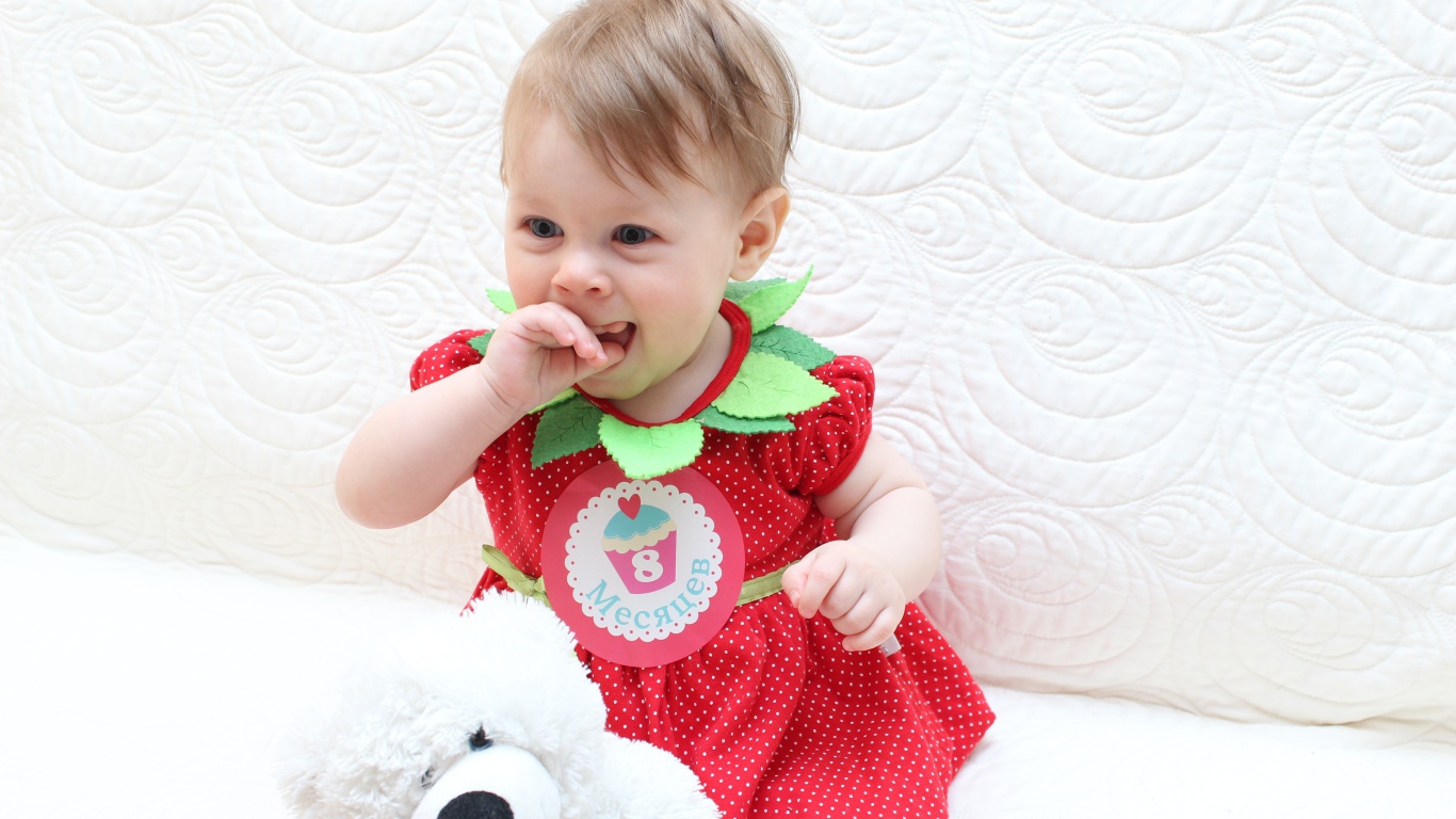 Маленькая девочка в красном платье с игрушкой на белом фоне