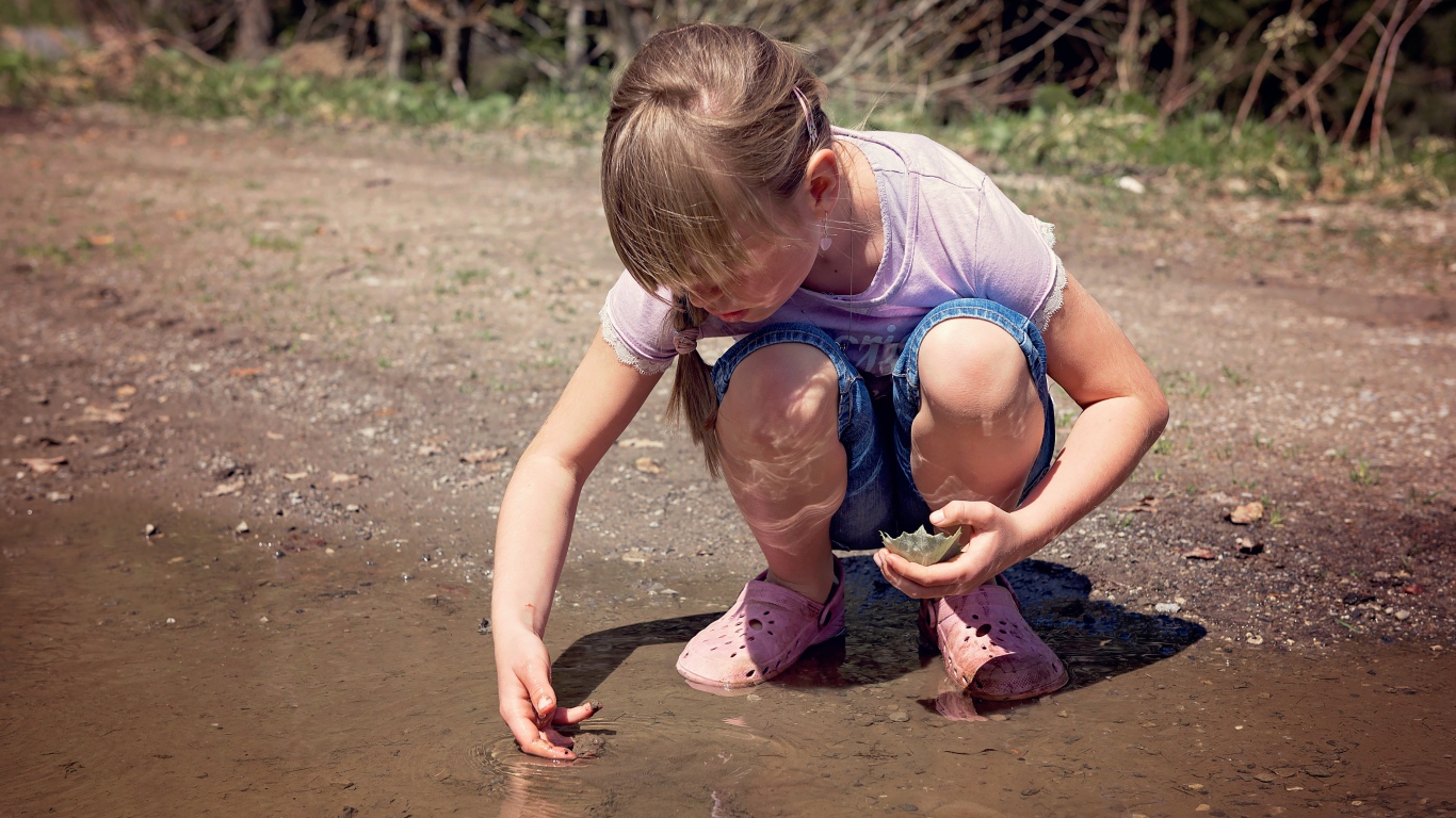 Маленькая девочка играет в луже 