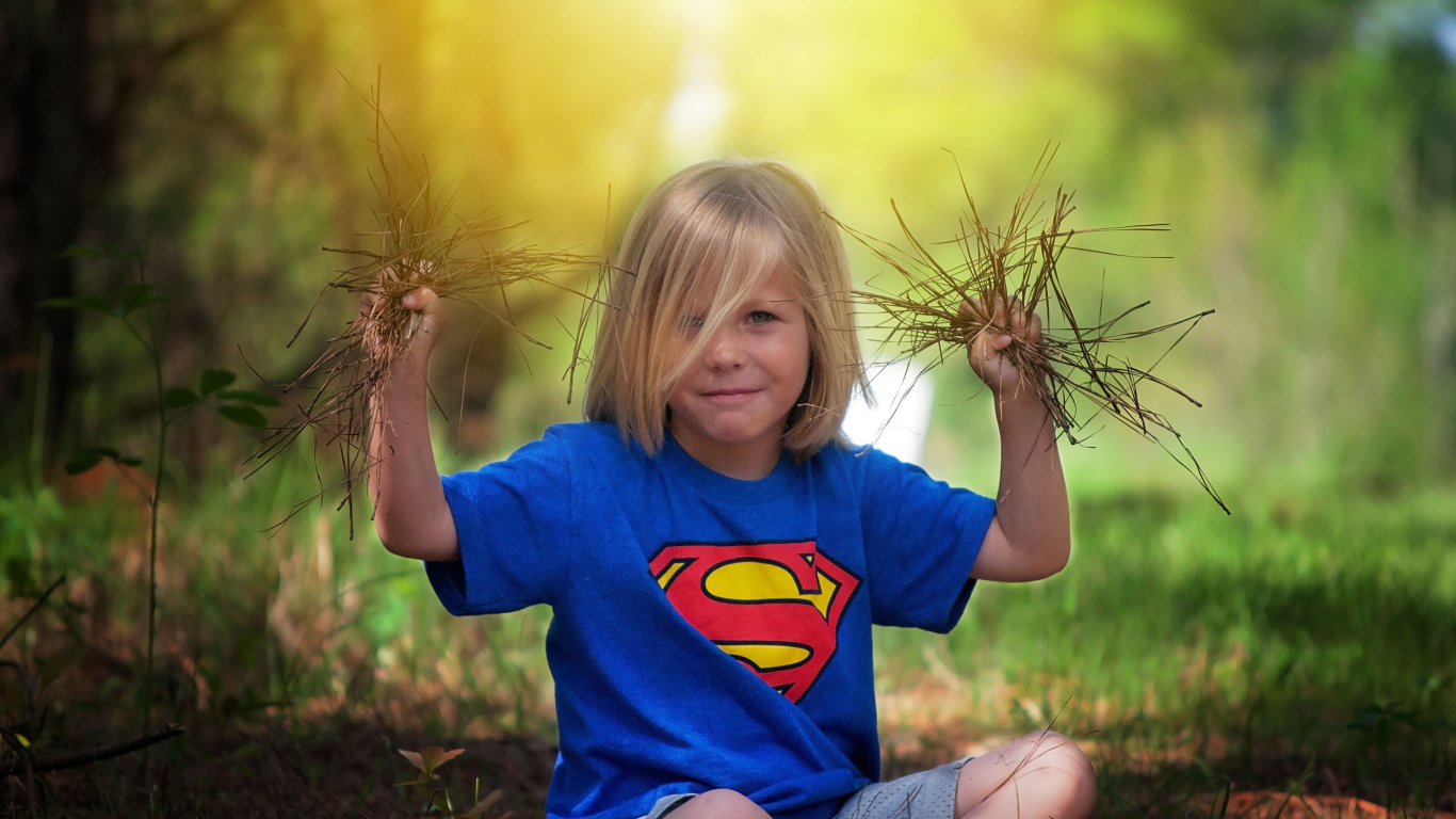 Маленькая девочка сидит на земле с травой