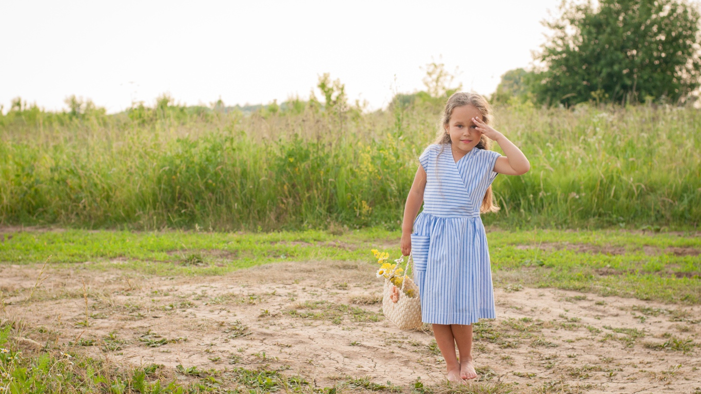 Маленькая девочка с сумкой на поле с травой 