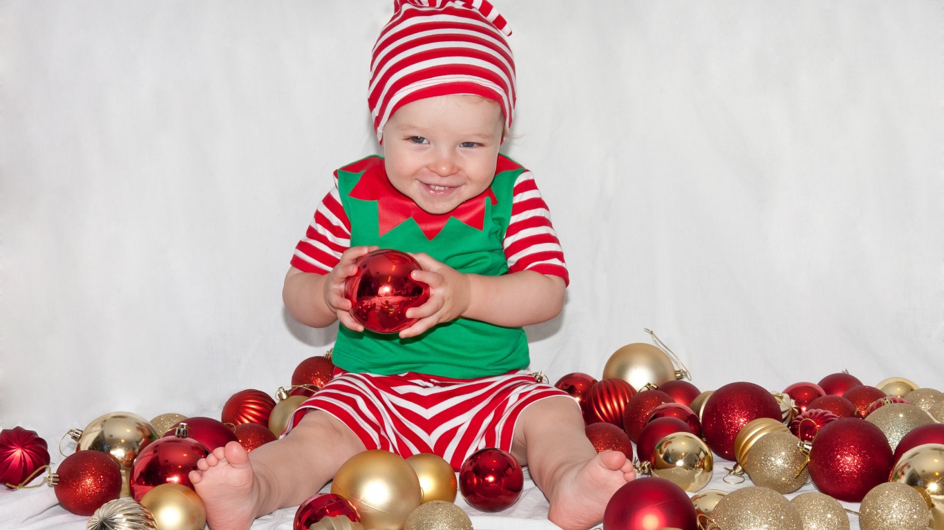 Маленький улыбающийся мальчик с елочными украшениями