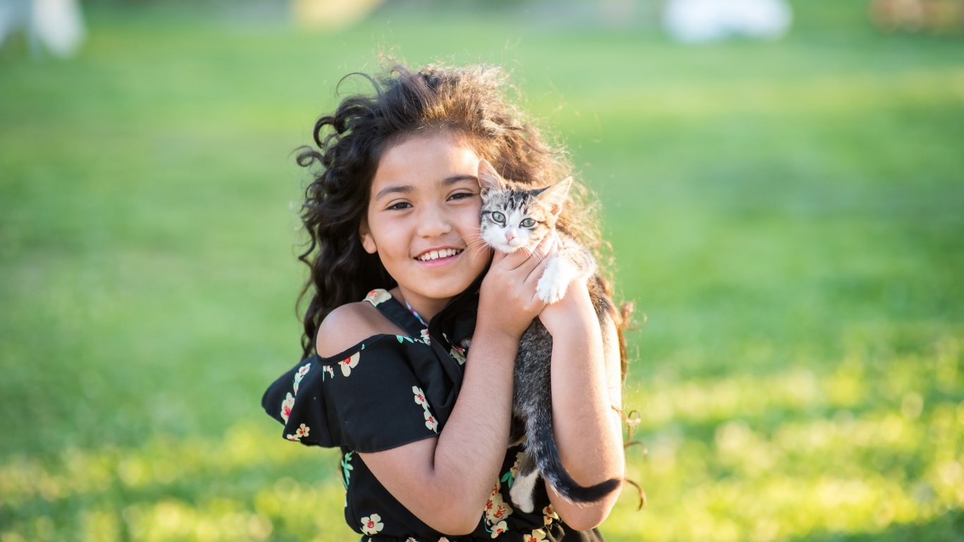 Маленькая улыбающаяся девочка с котенком в руках