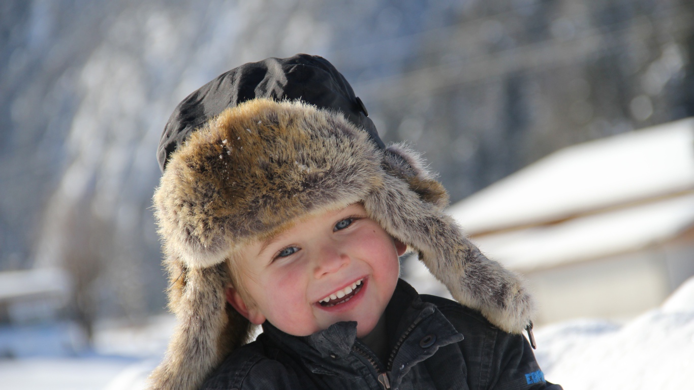 Улыбающийся  маленький мальчик в зимней шапке 