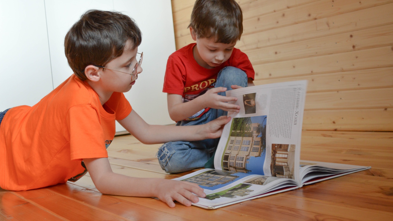 Два маленьких мальчика с книгой  на полу