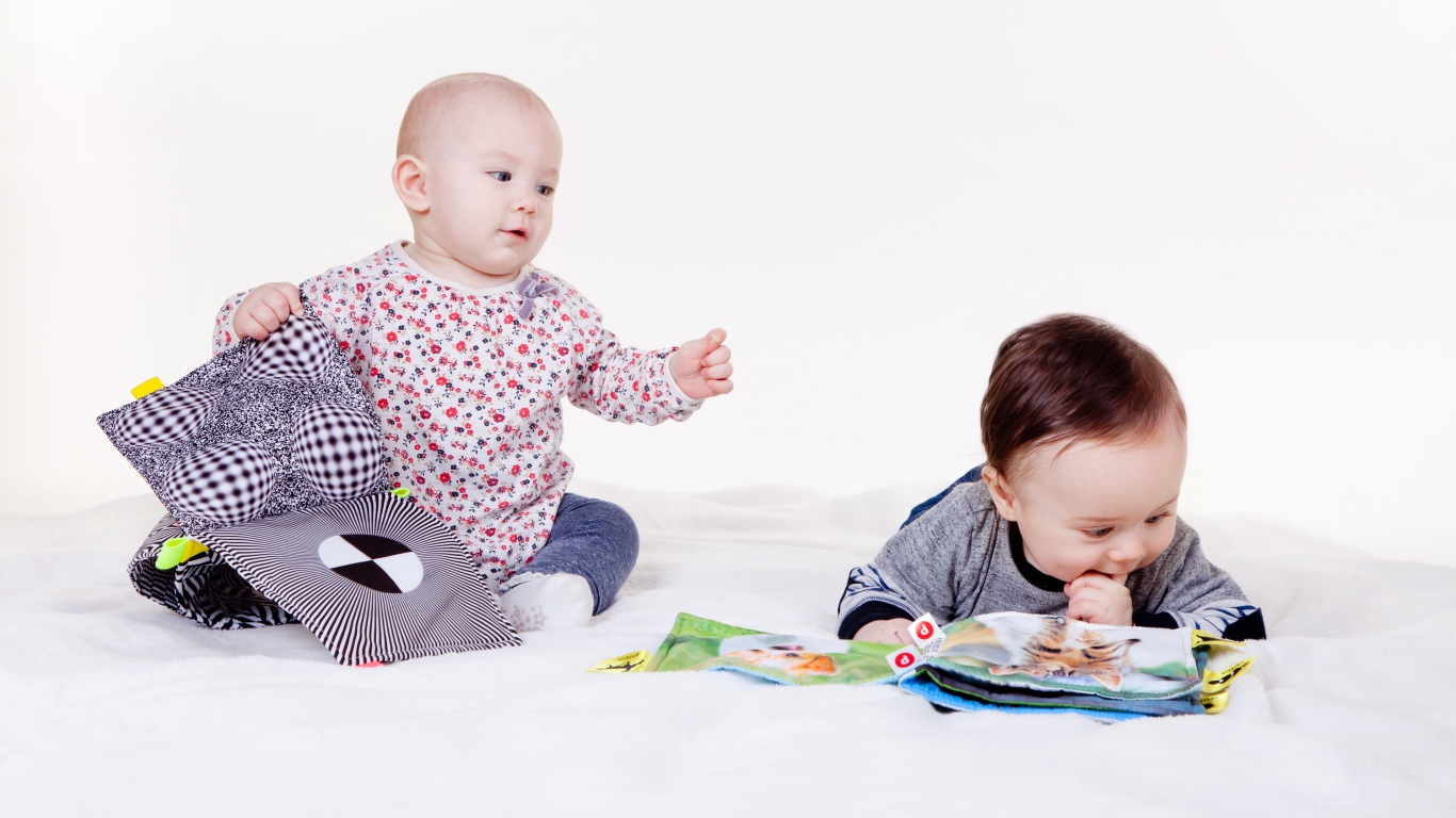 Два маленьких ребенка играют на белом фоне