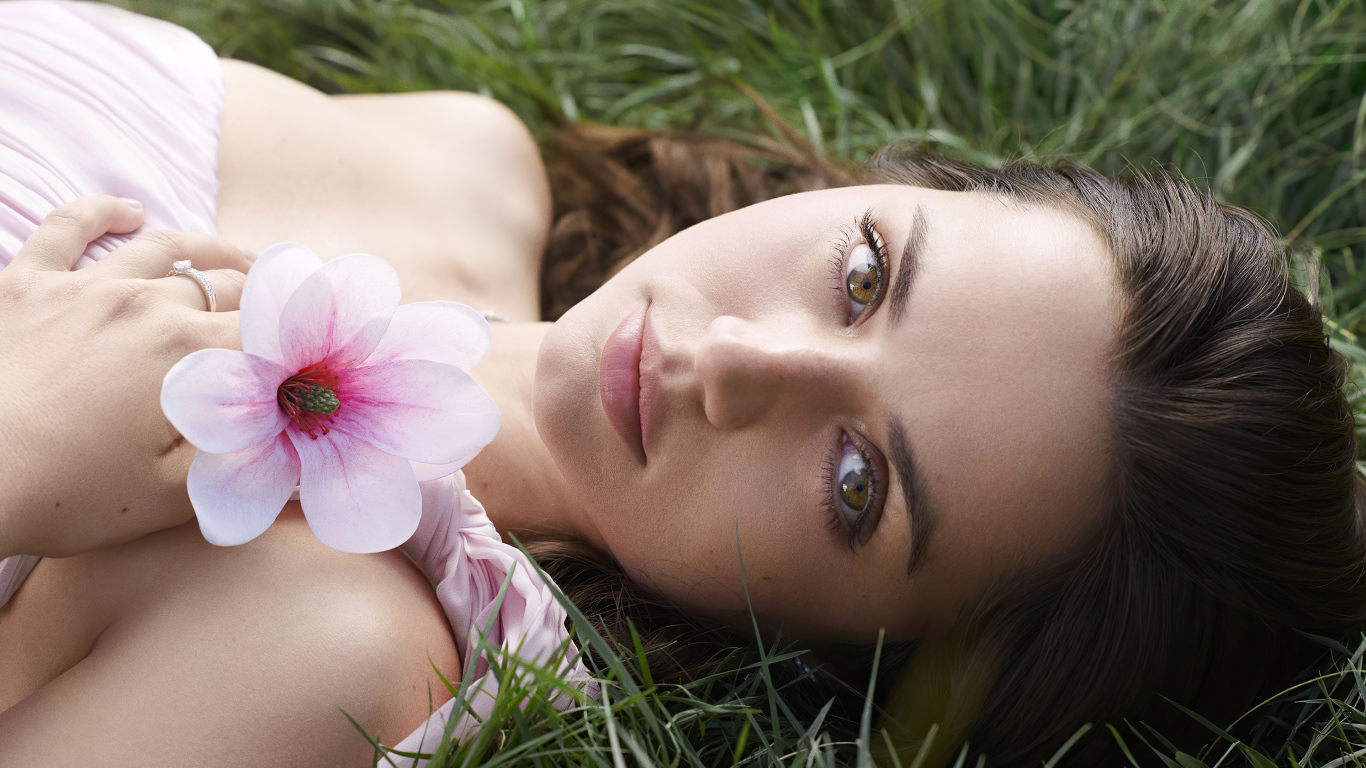 Актриса Ана де Армас лежит на зеленой траве с цветком