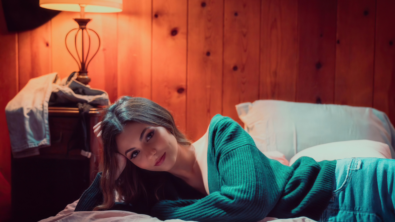 Актриса  Виктория Джастис в зеленом свитере на кровати