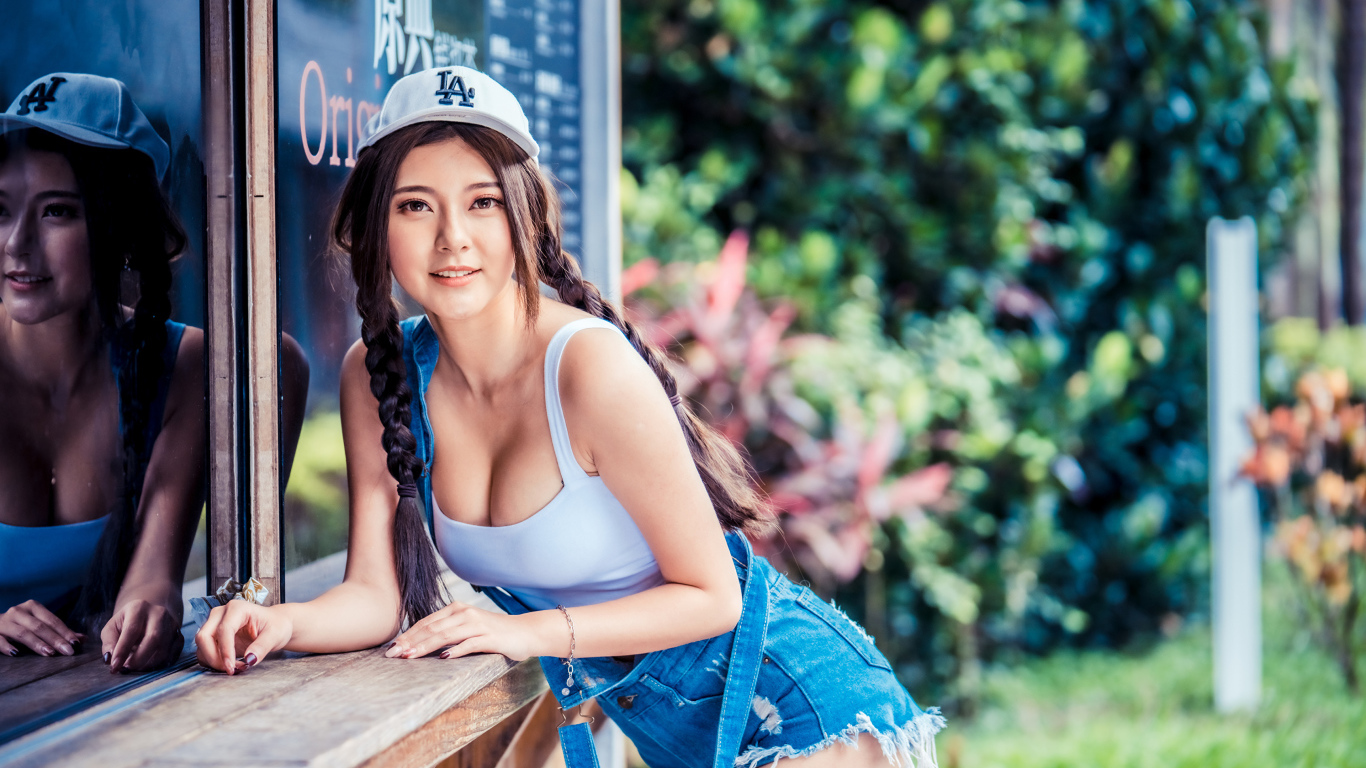 Спортивная девушка азиатка в кепке стоит у магазина