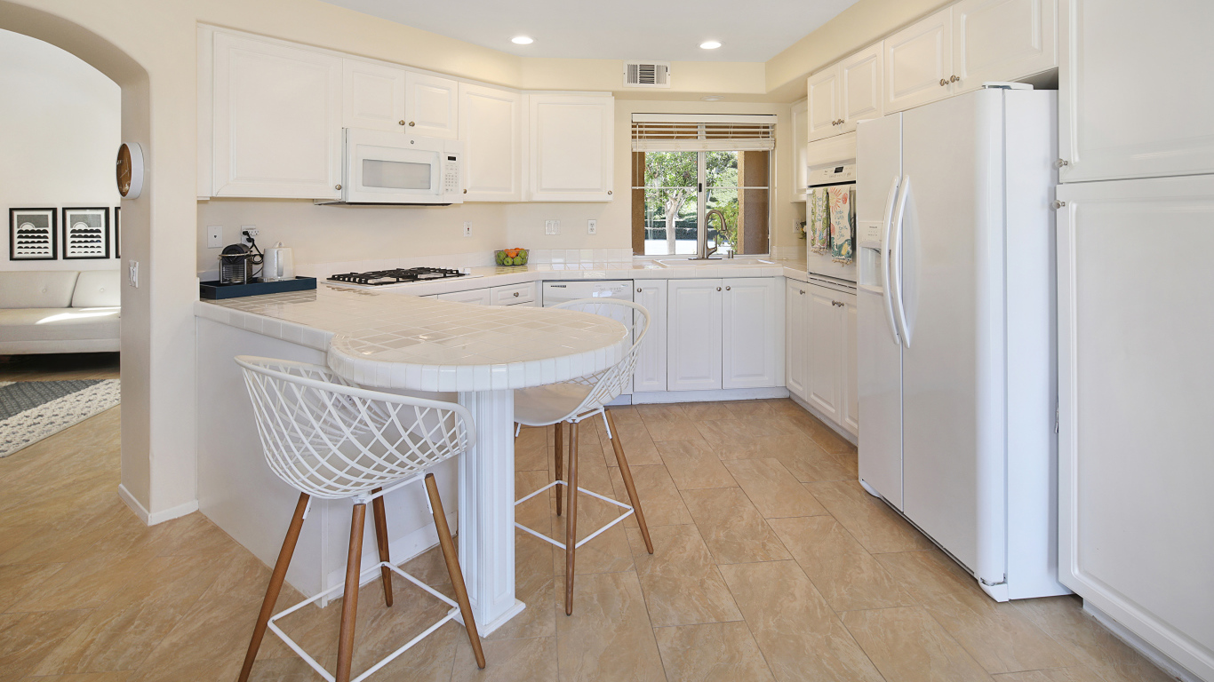 Большой холодильник и белая мебель на кухне 