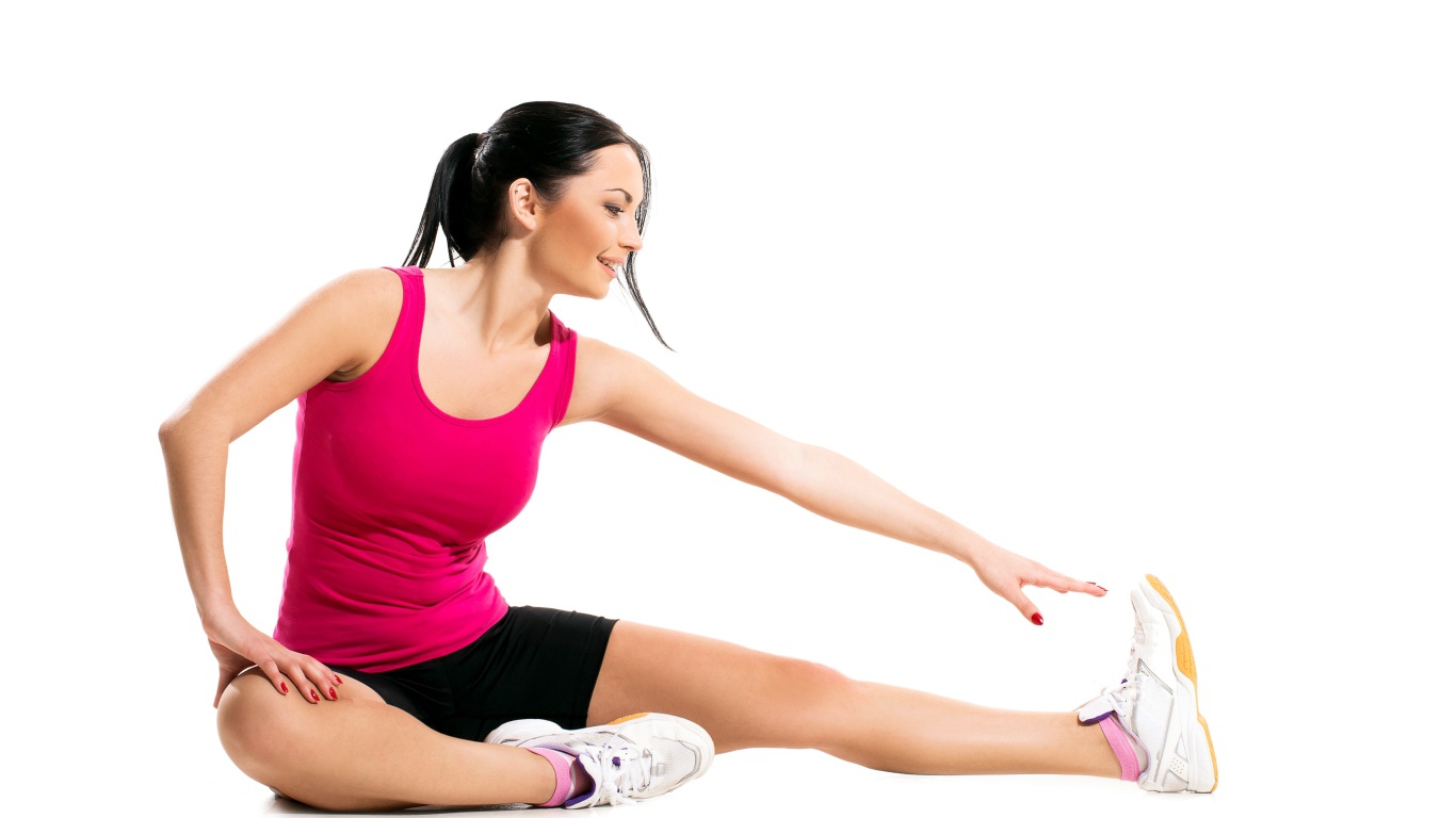 Спортивная девушка делает растяжку на белом фоне 