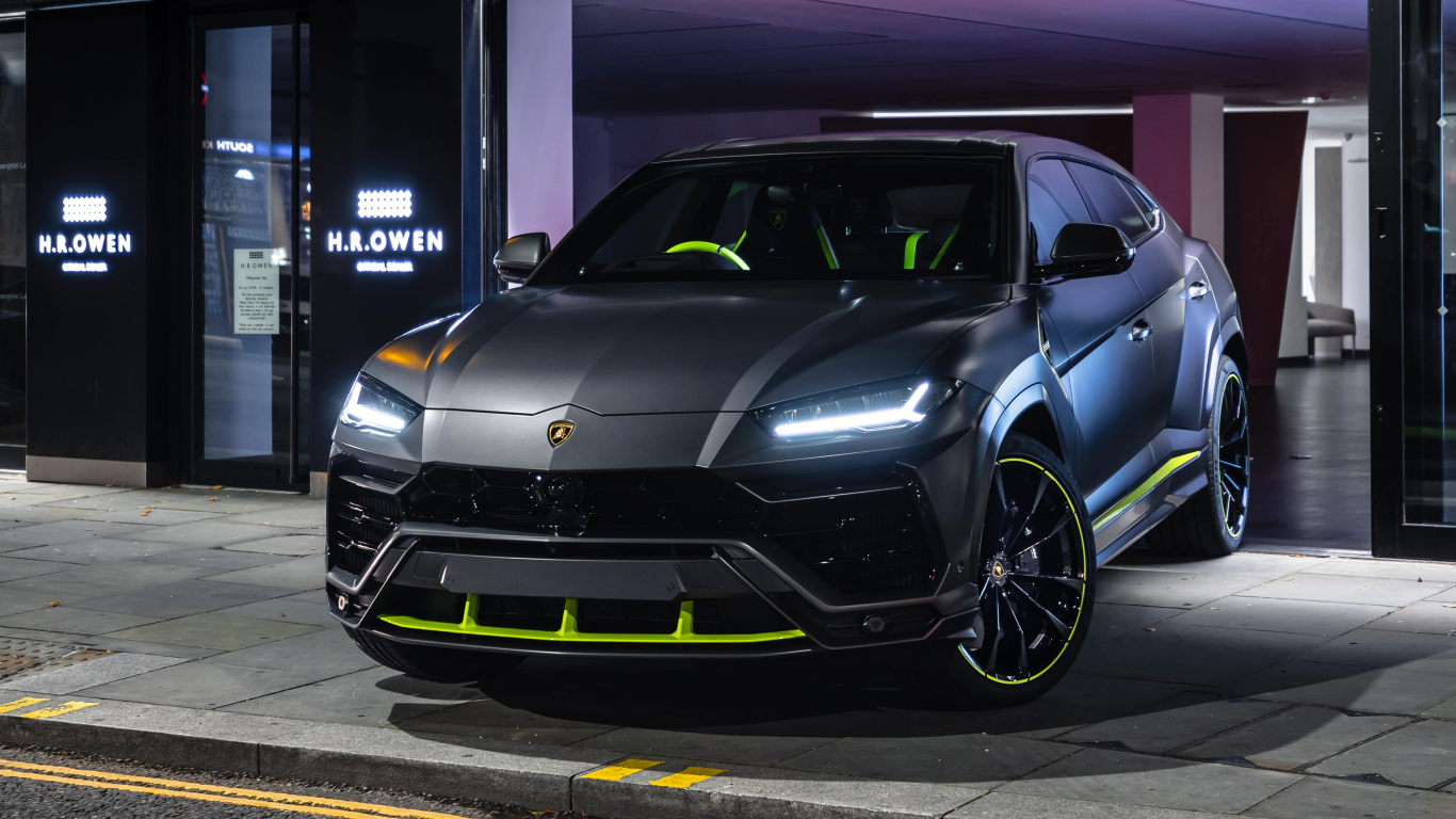 Серебристый Lamborghini Urus с включенными фарами
