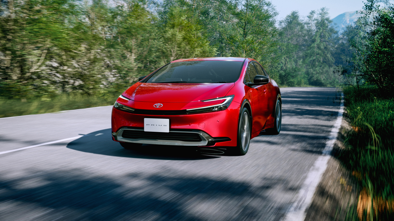 Красный автомобиль Toyota Prius HEV 2023  года на дороге