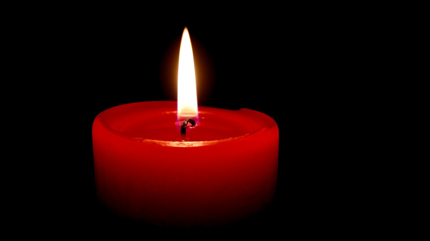 Зажженная красная свеча на черном фоне