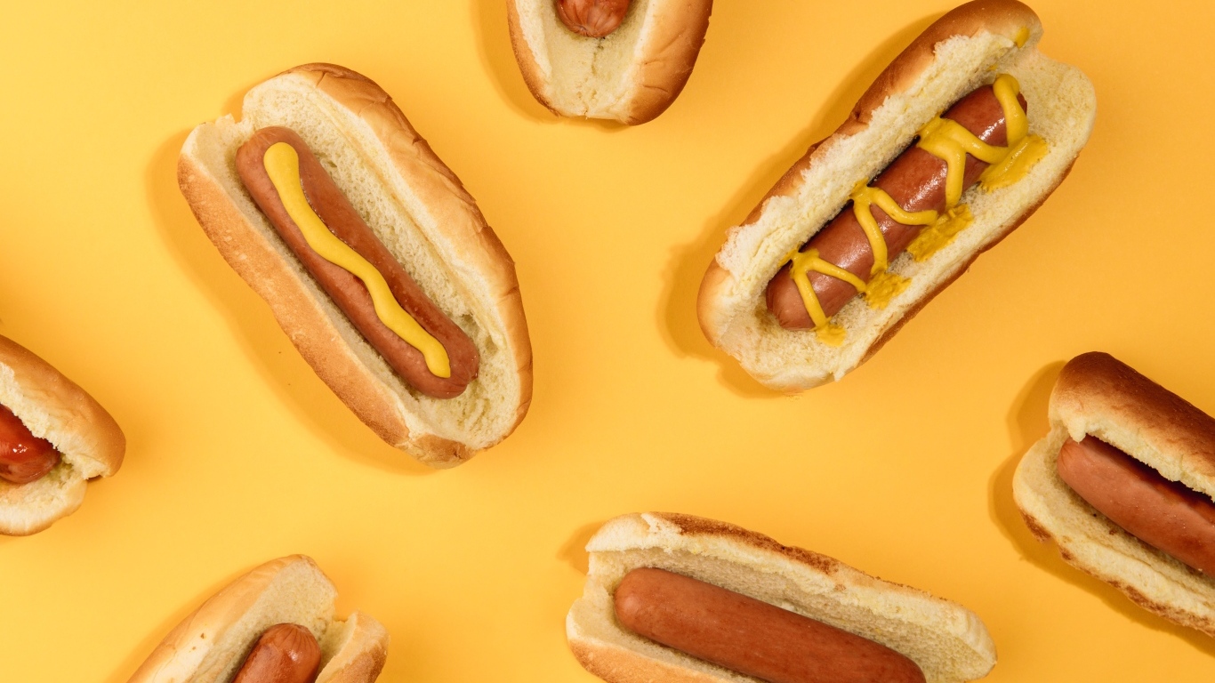 Аппетитные хот доги на желтом столе