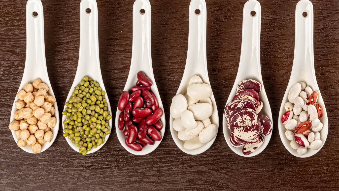 Бобовые зерна в белых ложках на столе