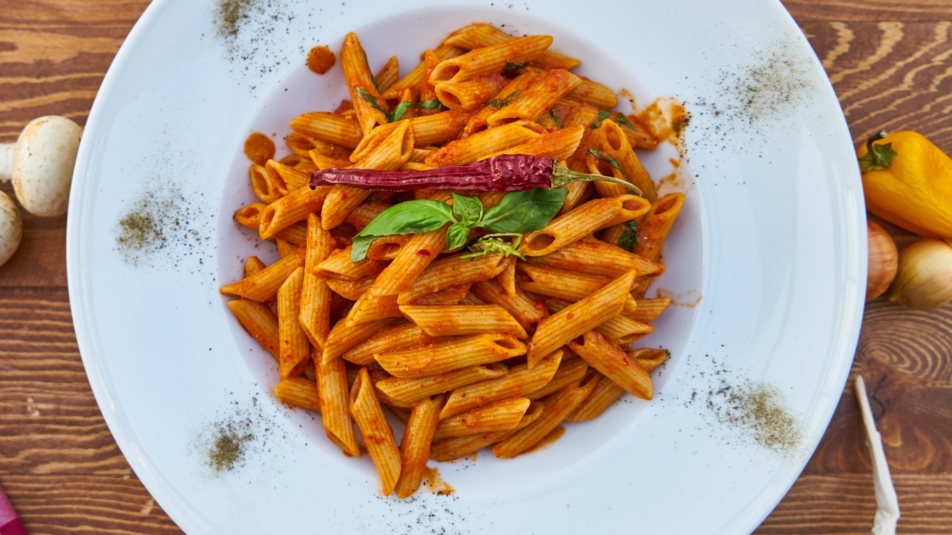 Вареные макароны на большой тарелке с красным перцем