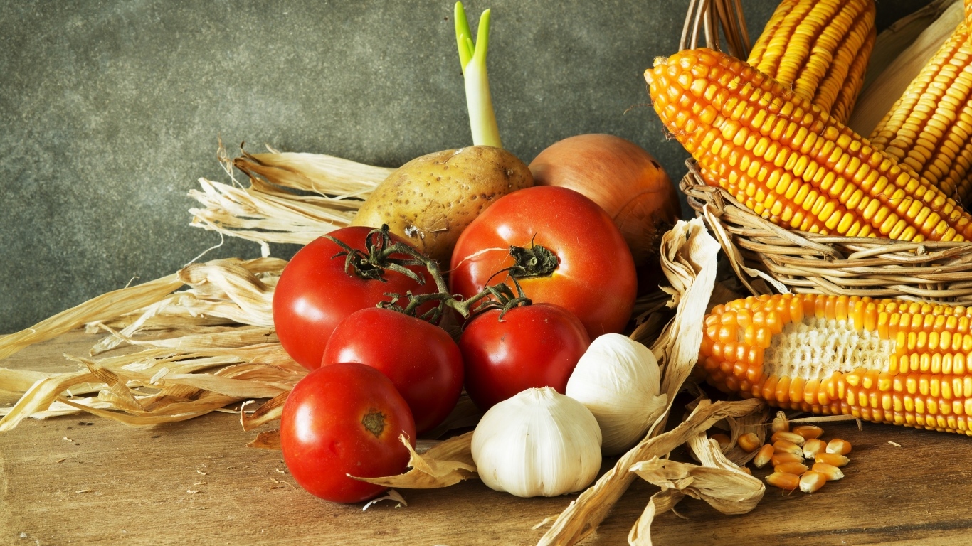 Кукуруза, чеснок и помидоры на столе