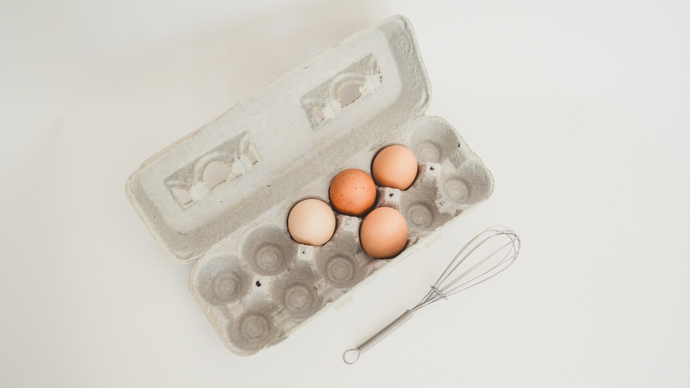 Четыре яйца в лотке на сером фоне