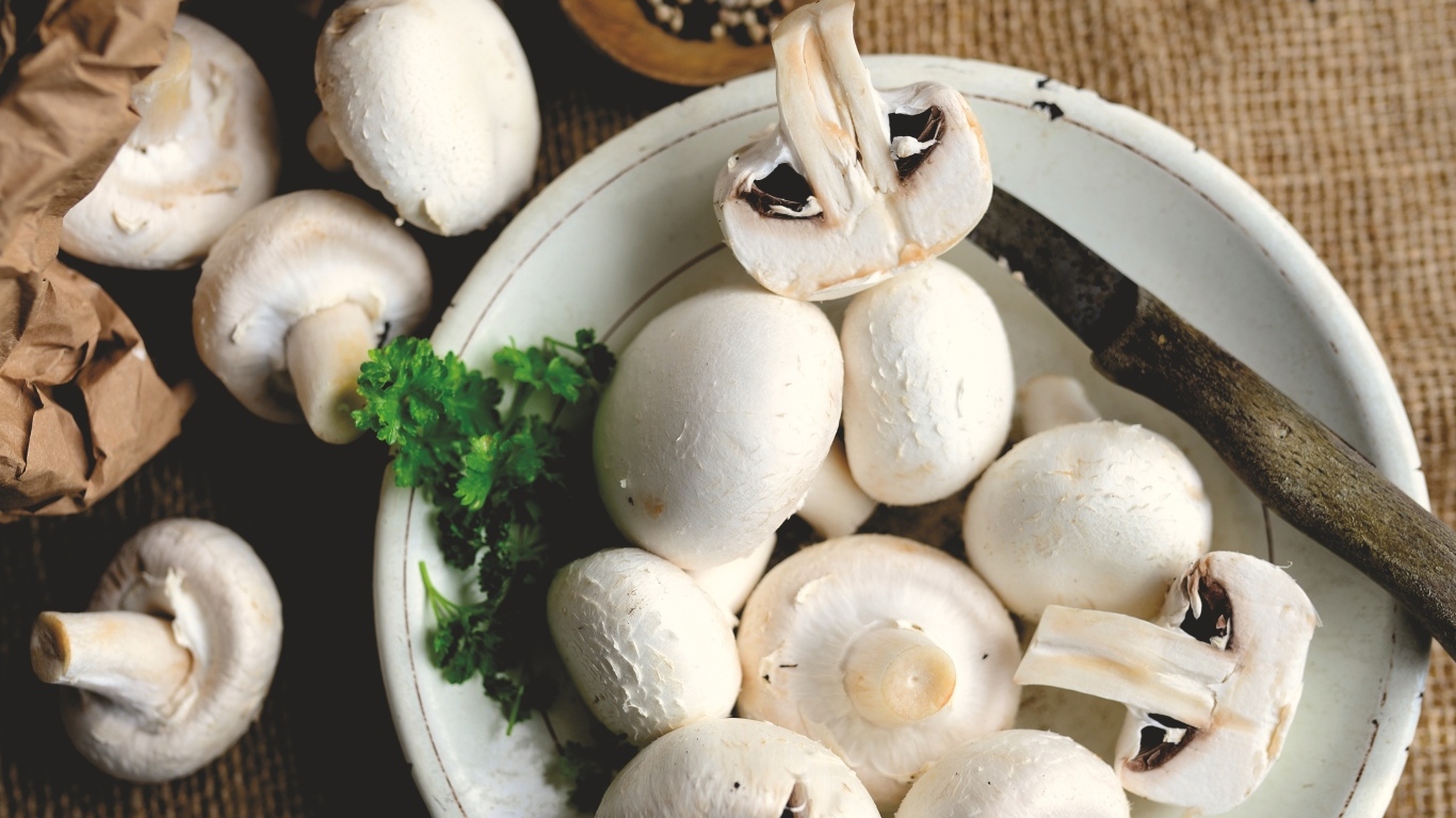 Свежие шампиньоны на тарелке на столе