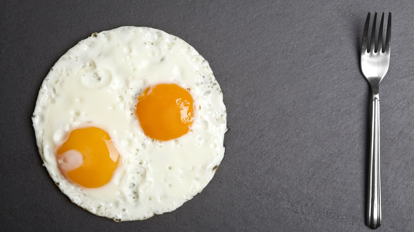 Яичница глазунья с вилкой на сером столе