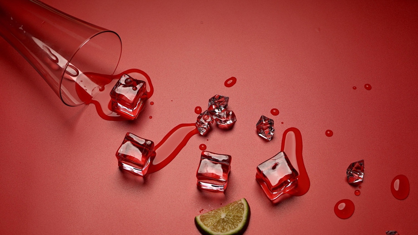Кубики льда на красном фоне с кусочком лайма и стаканом