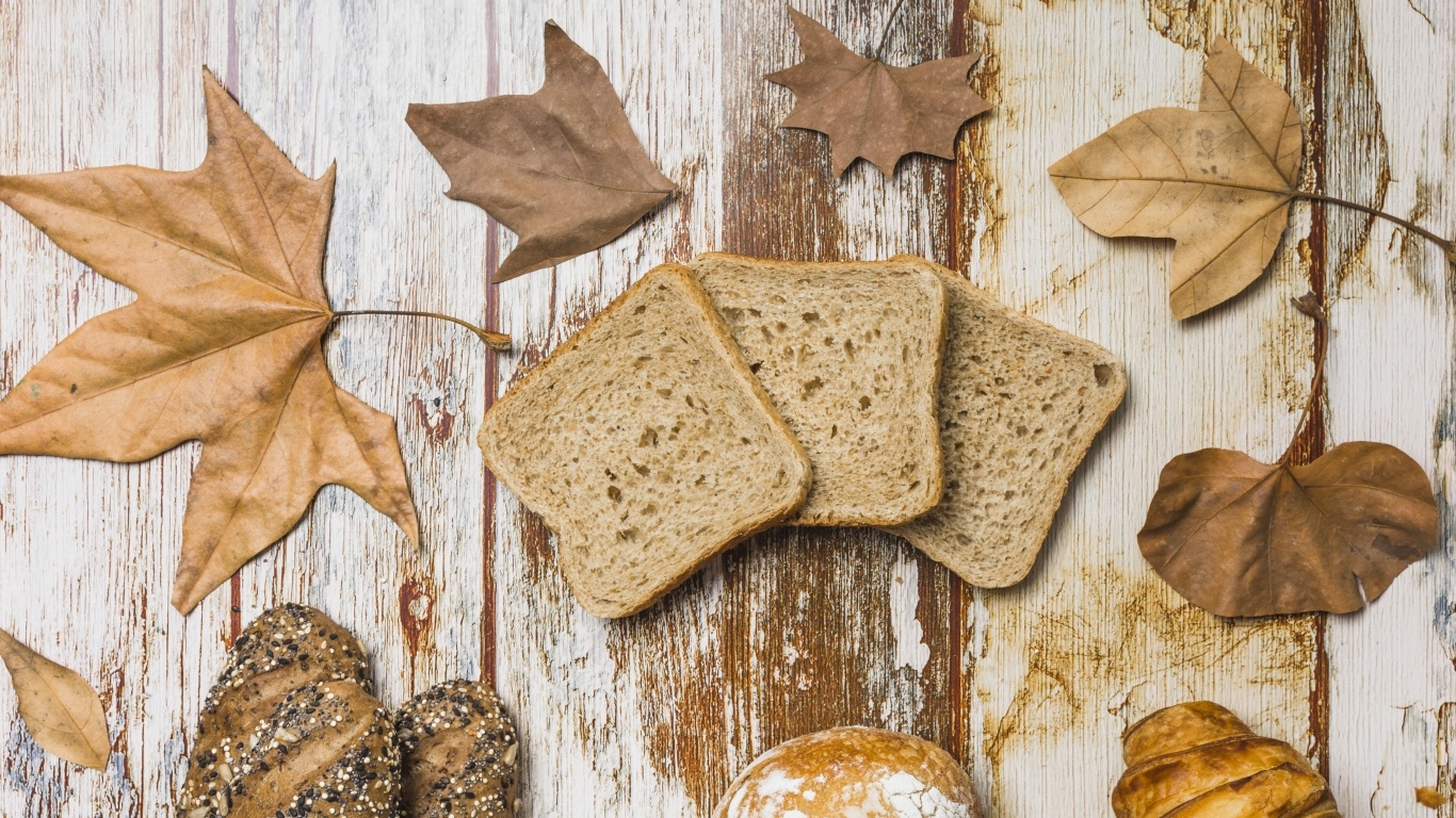 Куски хлеба с листьями на деревянном столе