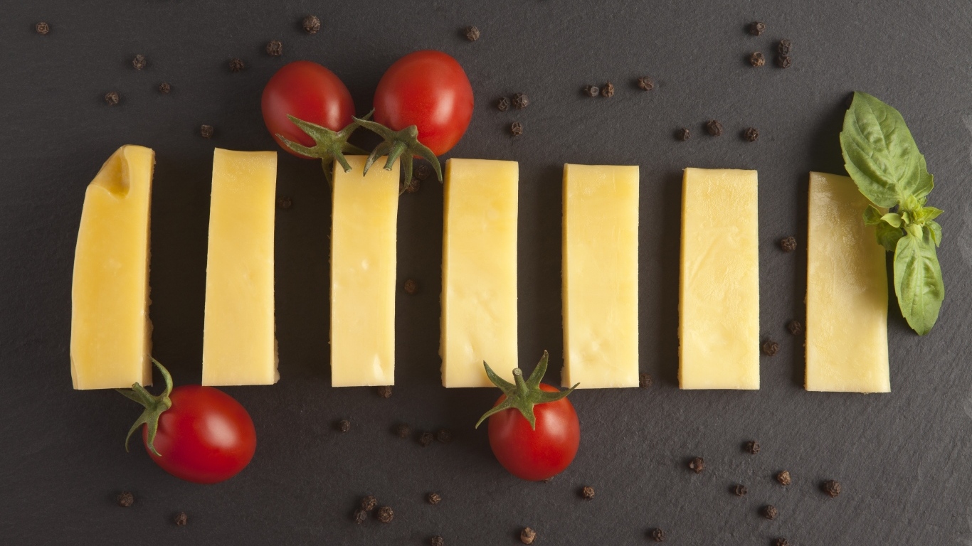 Кусочки сыра с помидорами на сером столе