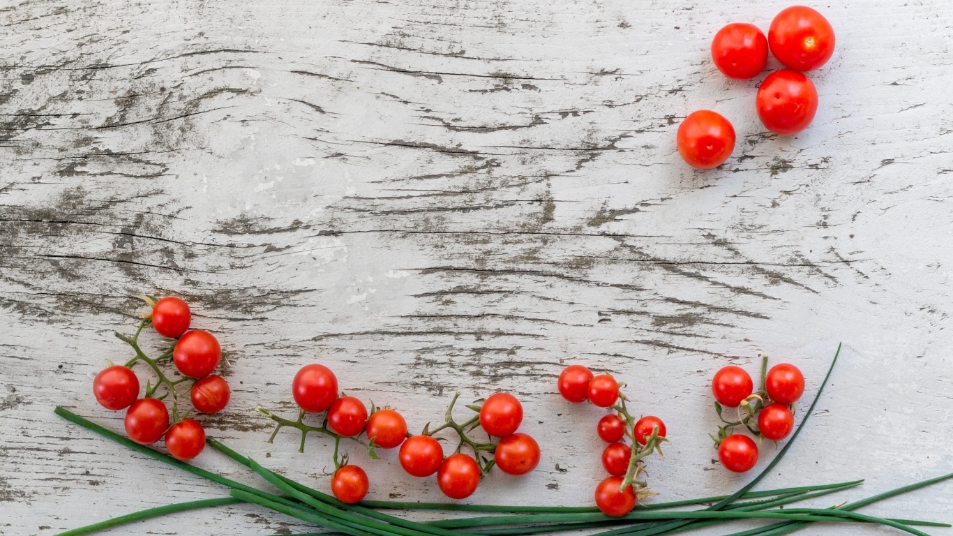 Красные помидоры с зеленым луком на деревянном столе