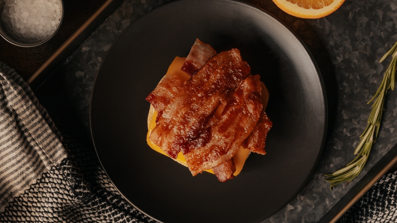 Бутерброд с сыром и жареным беконом на тарелке