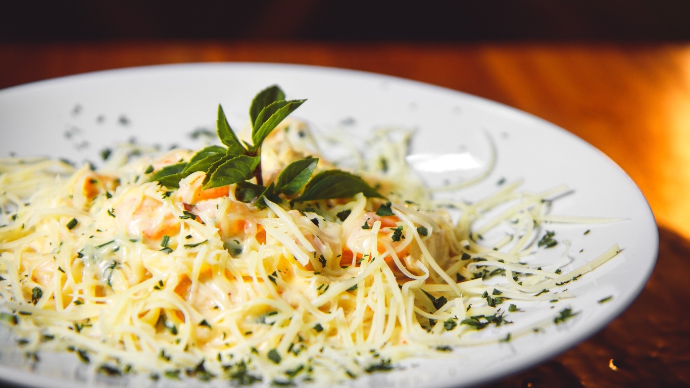 Спагетти с сыром и помидорами на белой тарелке