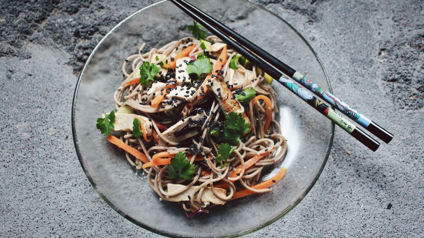 Спагетти с мясом и овощами в тарелке с китайскими палочками