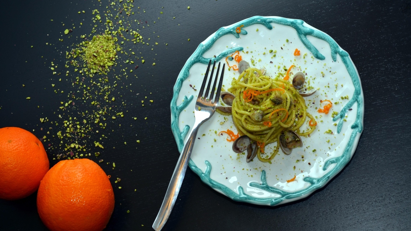 Спагетти с морепродуктами на столе с апельсинами