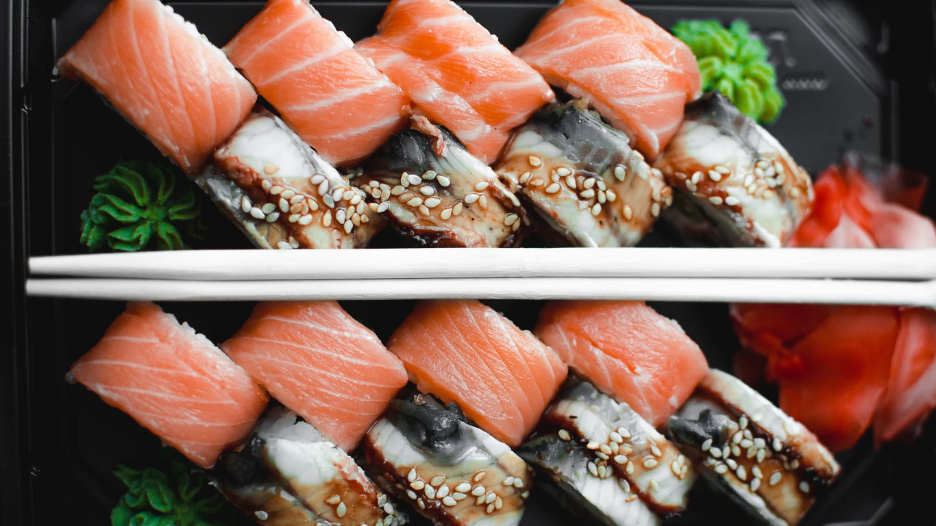 Суши с рыбой на черной тарелке с палочками